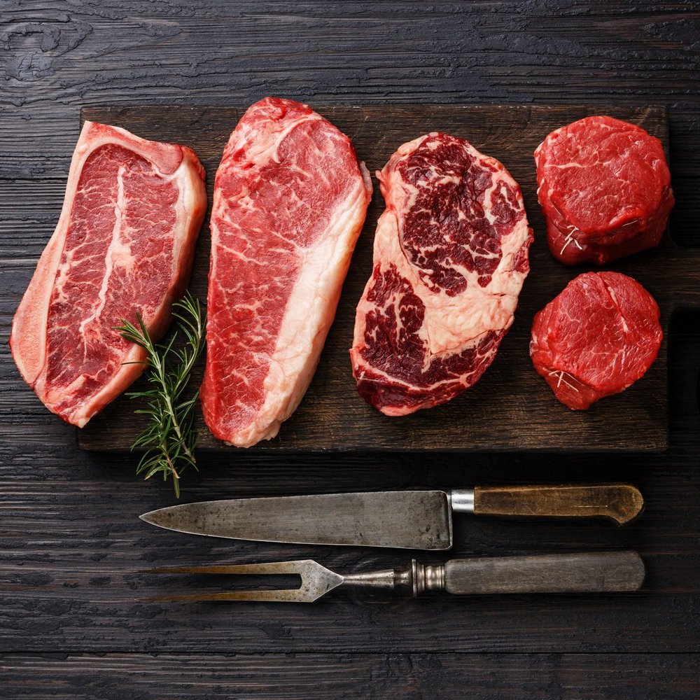 Juicy, medium-rare steak being sliced on a wooden cutting board, showcasing its tender pink interior and seared crust, with a carving knife and fork positioned for serving.